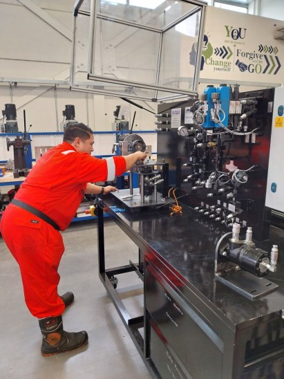 A man in a lab focused on repairing a complex machine, surrounded by tools and equipment.