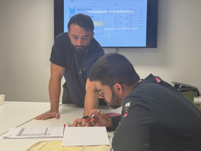 An instructor teaching a student sat around a table looking at paperwork.
